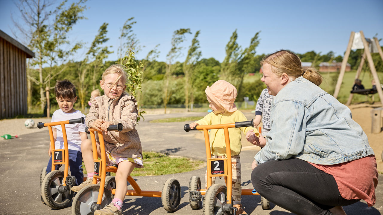 Voksen med børn på cykler i Børnehuset Dronningborg