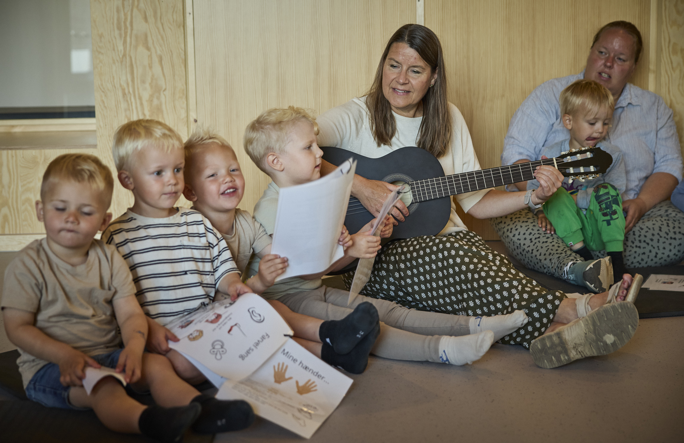 Voksen spiller guitar for børn i Børnehuset Dronningborg